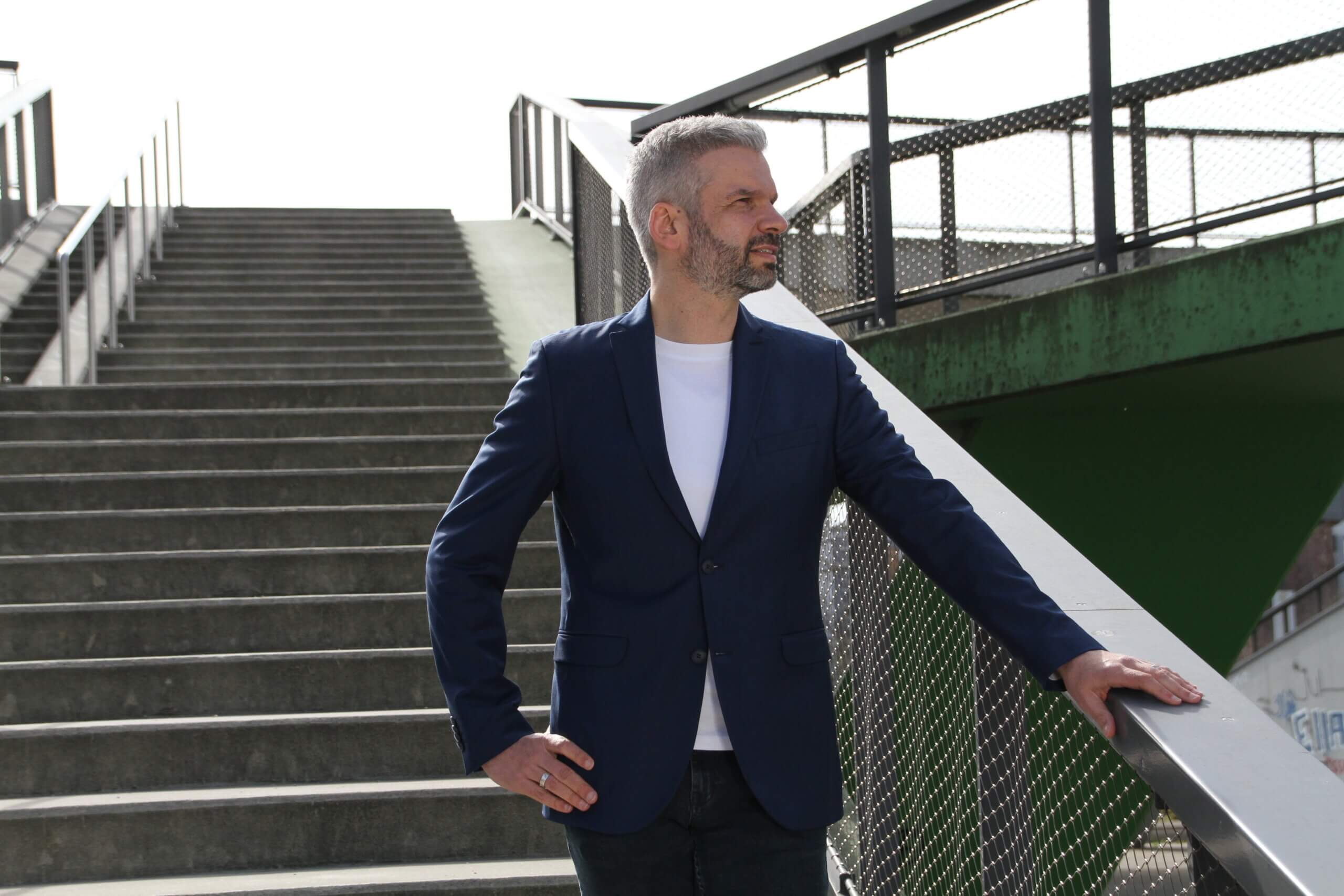 Eigenverantwortung Mitarbeiter abgeben – Business Coach steht an einer Außentreppe und blickt vorausschauend zur Seite